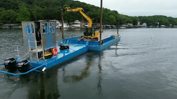 Excavator and spud barge under way