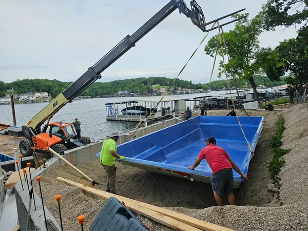 Crane setting a swimming pool from the barge