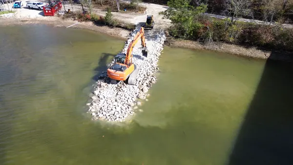 Excavator setting rip rap along the shoreline